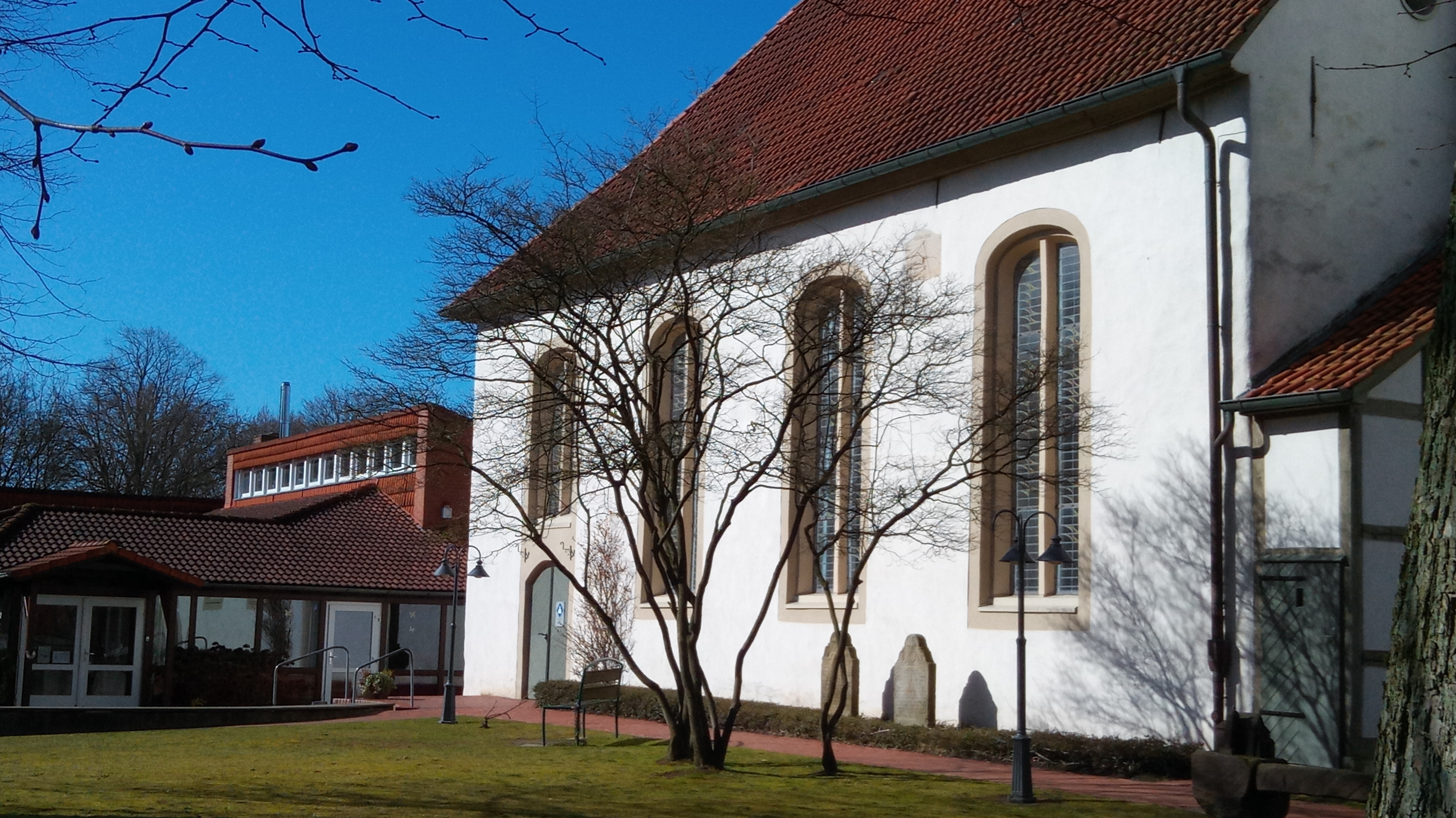 Kirche und Gemeindehaus mit dem neuen Edelstahlschornstein der Pelletheizanlage im Hintergrund